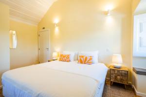 Un dormitorio con una gran cama blanca y una ventana en CASASUPERTUBOS - Óbidos, en Óbidos