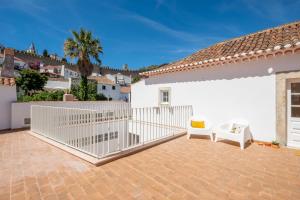 eine Terrasse mit 2 Stühlen und einem weißen Zaun in der Unterkunft CASASUPERTUBOS - Óbidos in Óbidos