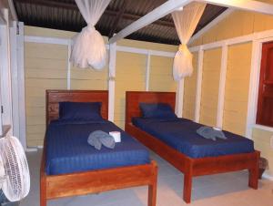 Don Som的住宿－Don Som Riverside Guesthouse，一间卧室配有两张带蓝色床单的床和大象。