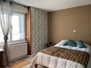 Un dormitorio con una cama con almohadas azules y una ventana en Le Crozet, en Arçon
