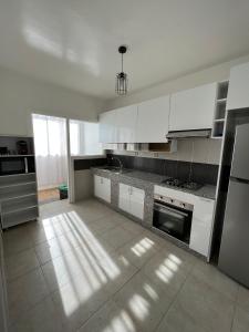 uma grande cozinha com armários e electrodomésticos brancos em Appartement Vue Sur Piscine Imi Ouaddar Taghazout em Agadir nʼ Aït Sa
