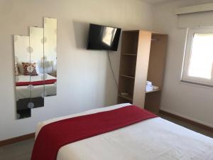 a bedroom with a bed and a tv on the wall at Santiago Guesthouse in Aveiro