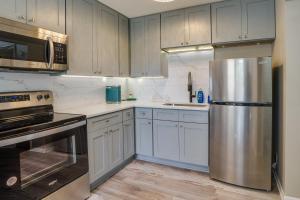 a kitchen with white cabinets and a stainless steel refrigerator at Cozy Minneapolis Duplex - 10 Mi to Downtown! in Minneapolis