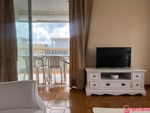 a living room with a television on a white cabinet at El Capricho in Benicàssim +46 photos