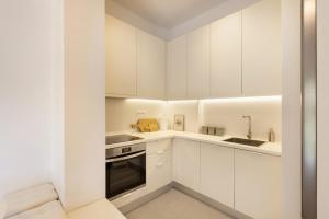 a white kitchen with white cabinets and a sink at Kerameikou25 small in Athens