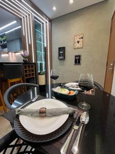 a table with a plate of food and a glass of wine at FLAT LUXO PREMIUM - Londrina Flat Hotel - 43m² #garagemgrátis in Londrina