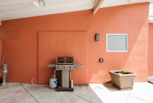 a barbecue grill against a orange wall with a door at Modern Paradise in LA with Private Pool in Los Angeles