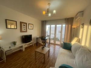 a living room with a couch and a tv and a table at Apartamento Mirador del Atlántico in Conil de la Frontera