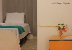 una habitación con una cama y un jarrón de flores sobre una mesa en Pousada Maravilha de Ará, en Praia de Araçatiba