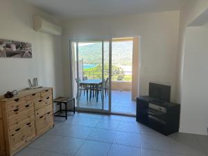 Una sala de estar con un televisor y una mesa con sillas. en Appartement avec piscine à 50 m de la plage, en Propriano