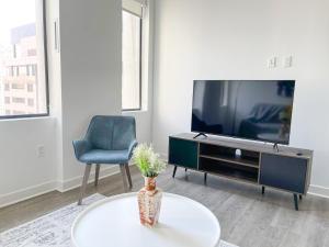 a living room with a tv and a table and a chair at Sleepover Exclusive 1BD 1BA Downtown Kansas City Apartments in Kansas City