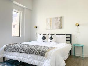a white bedroom with a large bed and a window at Sleepover Exclusive 1BD 1BA Downtown Kansas City Apartments in Kansas City