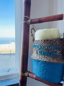 una cesta sentada en una silla junto a una ventana en Zambujeira Lounge, en Zambujeira do Mar