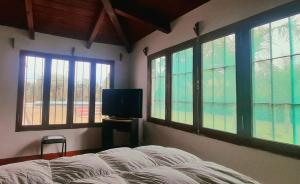 - une chambre avec un lit, une télévision et des fenêtres dans l'établissement Lugar clave, à Cerrillos