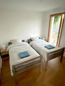 2 bedden in een witte kamer met een raam bij Neuf, vue panoramique, calme, spacieux, propre in Asnières-sur-Seine