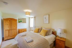 um quarto com uma cama grande e almofadas amarelas em The Steading at Castle Creavie Farm em Kirkcudbright