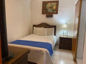 a bedroom with a bed with a blue blanket and a lamp at Hotel Nacional in Oaxaca City