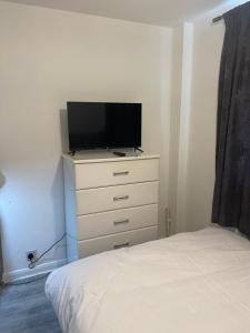 a bedroom with a dresser with a flat screen tv on it at Divine Room in London