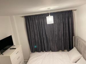 a bedroom with a bed and a black curtain at Divine Room in London