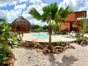 a resort with a palm tree and a swimming pool at Tropical Cabins Curaçao in Dorp Sint Michiel