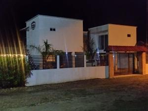 una casa bianca con una recinzione di fronte ad essa di notte di Chiriguare Parrilla 