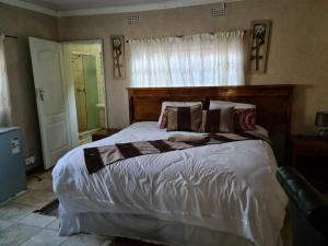 a bedroom with a large bed with a wooden headboard at The CabinGuesthouse in Gaborone