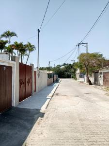 una calle vacía con una valla y palmeras en Flat Solife 3 Cabo Frio-Búzios, en Cabo Frío