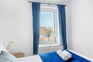 a bedroom with a window with blue curtains at 2 Bed Waterfront Apartment, 3 Minutes From Train Station in Nottingham