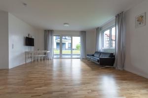 a living room with a black couch and a wooden floor at T&K Apartments - Bergisch Gladbach - 7 Comfortable Apartments - 20 min to Fair Messe Cologne in Bergisch Gladbach