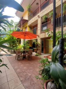 eine Terrasse mit einem orangenen Sonnenschirm, einem Tisch und Stühlen in der Unterkunft Hotel Villa Prats in Manuel Antonio