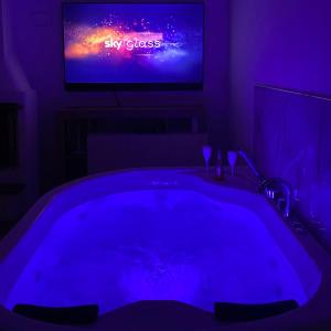 Habitación oscura con bañera frente a una TV. en Casa vacanza “oasi” en Salerno