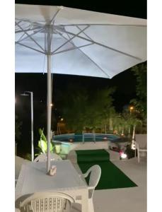 una sombrilla blanca sentada en una mesa junto a una piscina en Casa vacanza “oasi” en Salerno