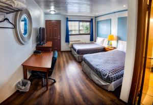 Habitación de hotel con 2 camas, escritorio y escritorio. en Budget Inn en The Dalles