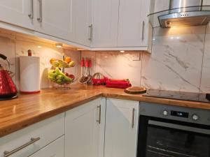 cocina con armarios blancos y encimera de madera en Stylish 1 bedroom Haven en Coventry