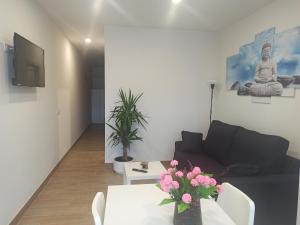 sala de estar con sofá y mesa con flores en Apartamentos Silgar Plaza en Sanxenxo