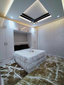 Appartement de luxe à 7 min de Centre de ville في مراكش: غرفة نوم بيضاء مع سرير كبير وسقف