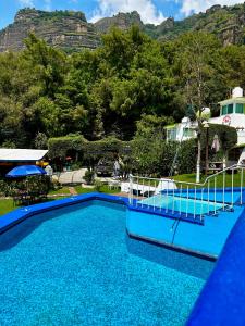 una piscina azul con montañas en el fondo en BUNGALOWS ANDREA, en Tepoztlán