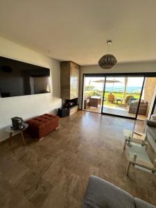 ein großes Wohnzimmer mit einem Sofa und einem TV in der Unterkunft OCEAN VIEW, Prestigia Plage des Nations in Sidi Bouqnadel