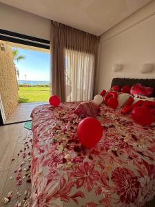 ein Schlafzimmer mit einem großen Bett mit roten Kissen in der Unterkunft OCEAN VIEW, Prestigia Plage des Nations in Sidi Bouqnadel