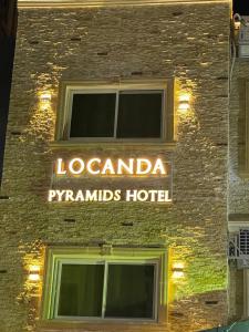 un panneau d'hôtel sur le côté d'un bâtiment dans l'établissement Locanda Pyramids Hotel, au Caire