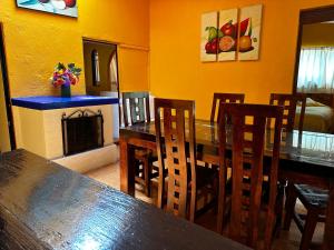 une salle à manger avec une table, des chaises et une cheminée dans l'établissement BUNGALOWS ANDREA, à Tepoztlán