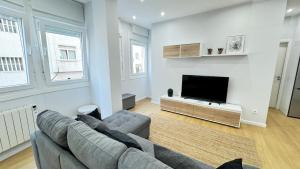 sala de estar con sofá y TV de pantalla plana en Comodidad cerca de la playa.. a un paso de todo! en A Coruña