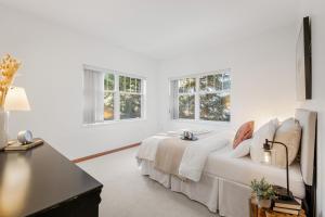 a white bedroom with a bed and two windows at Desirable Blueberry Hill in Whistler