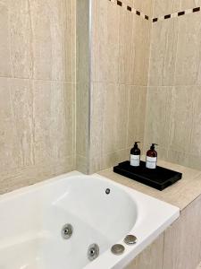 a white bath tub with two bottles of soap at Complejo Hermogenes in San Juan +3 photos