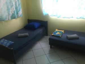 two beds in a small room with a window at Hinarani Home Haapiti in Haapiti