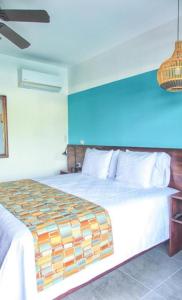 1 dormitorio con 1 cama grande y pared azul en La Fortuna Lodge by Treebu Hotels, en Fortuna