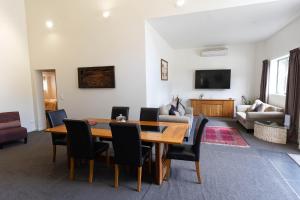een woonkamer met een houten tafel en stoelen bij Tui Lodge Oakura 