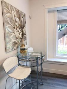 einen Glastisch und Stühle in einem Zimmer mit Gemälde in der Unterkunft Si & Daniel Home Near YVR Airport & Skytrain Separate Entry Free Parking in Richmond