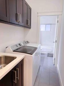 uma cozinha branca com um lavatório e um fogão em Si & Daniel Home Near YVR Airport & Skytrain Separate Entry Free Parking em Richmond