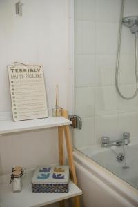 a book sitting on a shelf next to a bath tub at Spacious 3 bedroom apartment free parking! in Kent